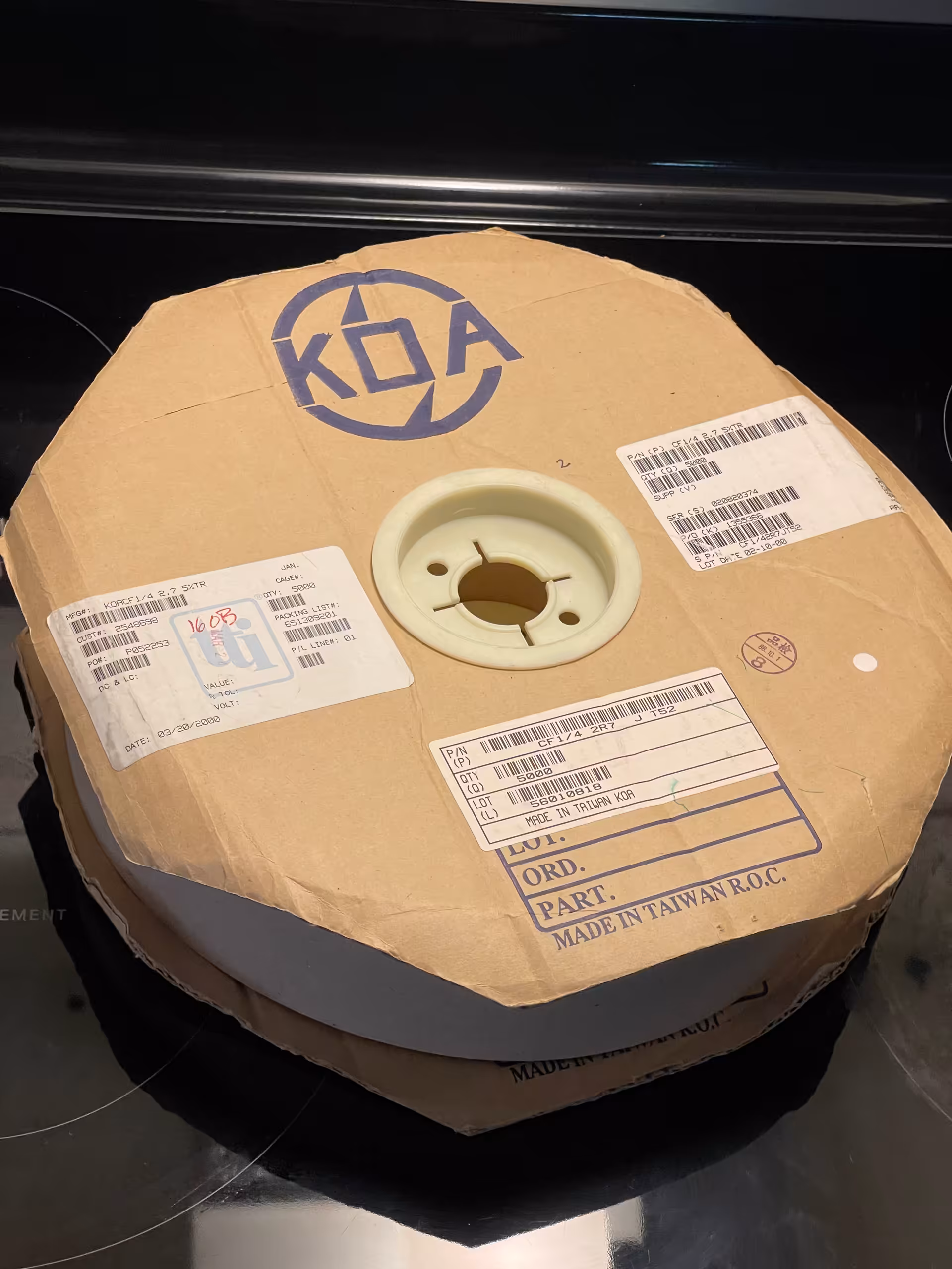 KOA logo reel with three labels: KOACF1/4 2.7 5 percent TR, CF1/4 2R7 J T52, QTY 5000, MADE IN TAIWAN