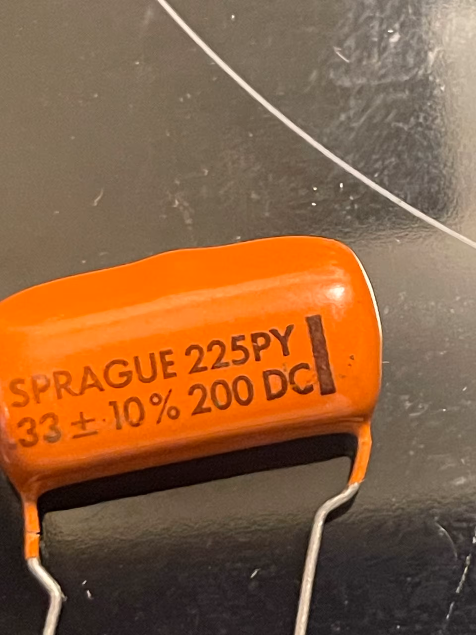 Orange dipped film capacitor filling the frame, printed SPRAGUE 225PY and 33 plus or minus 10 percent 200 DC.