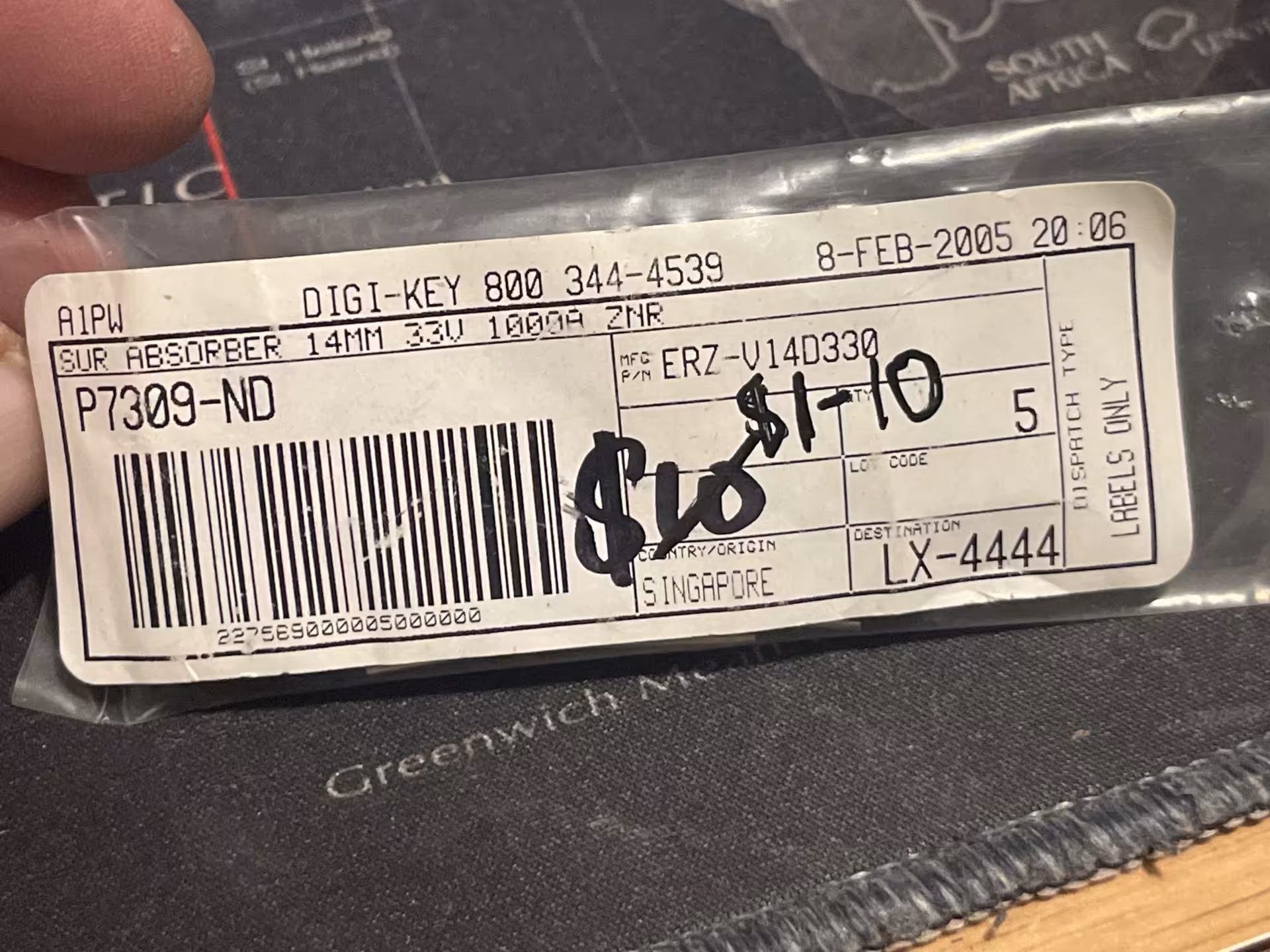 The distributor label held closer, showing the packing date of 8 February 2005, the country of origin Singapore, and the quantity of five.